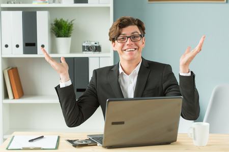 Technologies, emotions and business people concept - handsome man spreading his hands while he is working at computer, because he has some problemsの写真素材