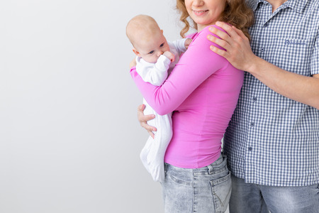 Family, childhood and parenthood concept - close up of father, mother holding cute baby over white background with copy spaceの写真素材