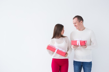 People, christmas, birthday, holidays and valentines day concept - happy young man and woman with gift boxes on white background with copy spaceの写真素材