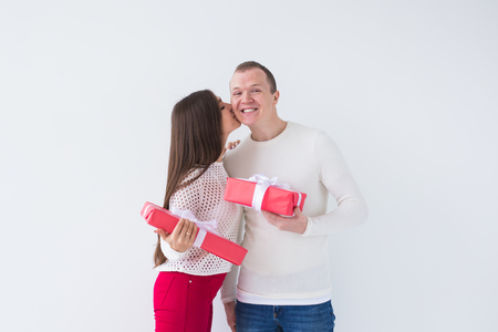 People, christmas, birthday, holidays and valentines day concept - happy young man and woman with gift boxes on white backgroundの写真素材