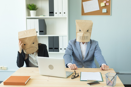 Business, emotions and people concept - Two angry and exhausted workers at working place. People wearing the packages on their heads with pictured emotionsの写真素材