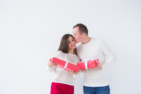 Christmas, holidays, Valentines day and birthday concept - Happy man and woman holds boxes with gifts on white backgroundの写真素材
