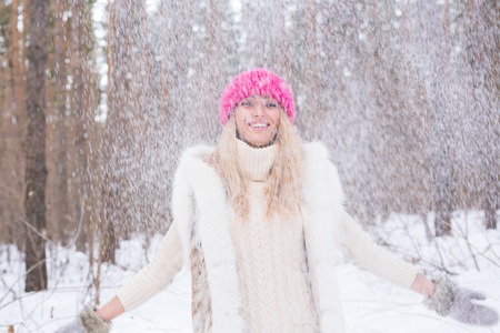 Happy young woman plays with a snow at snowy forest outdoorの写真素材