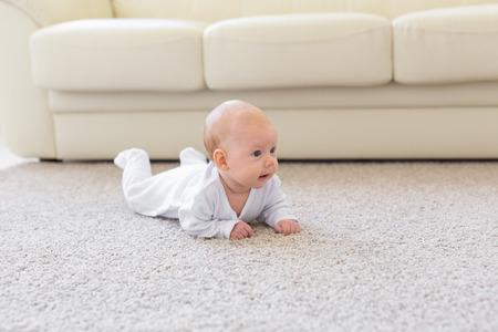 Childhood, infant and people concept - baby girl learning to crawl on the floorの写真素材