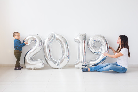 New 2019 Year is coming concept - Mother with her baby son sitting near silver colored numbers indoors.の写真素材