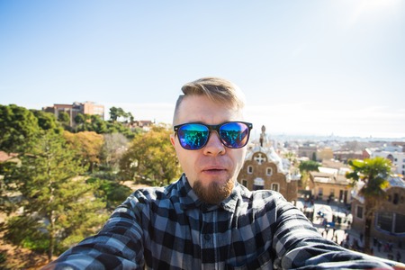 Travel and holidays concept - Handsome man looking at camera taking photo with smart phone smiling...
