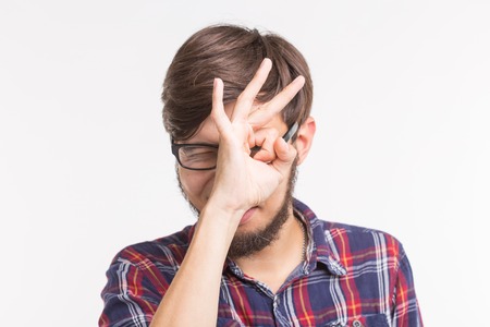 Young creative man holding fingers near eyes like glasses. Fun concept,の写真素材