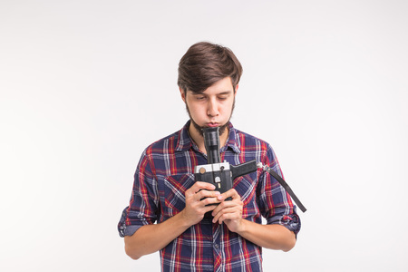 Technology, photography and people concept - Handsome man in plaid shirt taking a photo on vintage camera on white background with copy spaceの写真素材