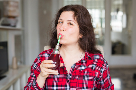 Health, food, diet and people concept - young woman drinking natural juice in a bottle and it seems to be tastyの写真素材