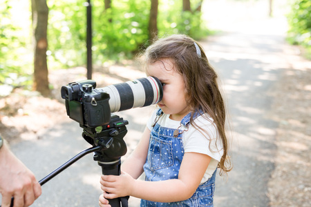 Hobby, profession, children and photographer concept - child with camera in forestの写真素材