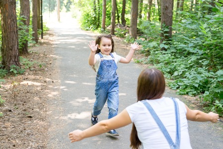 Nature, family, people concept - Adorable little kid girl and young woman in beautiful forest. Daughter running to motherの写真素材