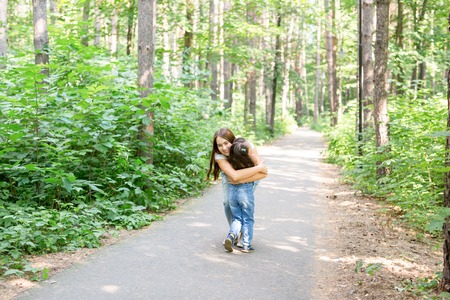 Parenthood, nature and children concept - mother and daughter hugging in the summer parkの写真素材