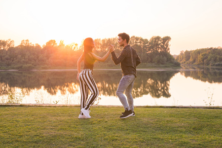 Romantic, social dance, people concept - young couple dancing near the lake in sunny dayの写真素材