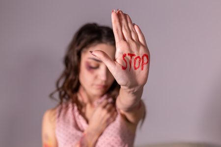 Domestic violence, protesting and people concept - brunette woman expressing denial with NO on her hand on grey roomの写真素材