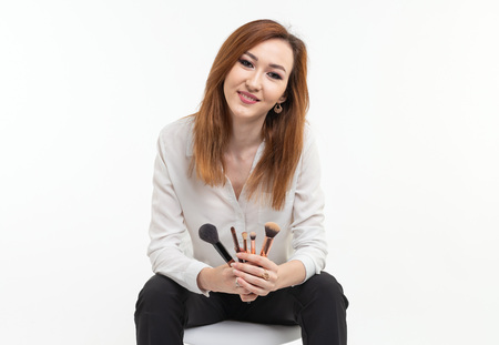 Attractive visagist or korean make-up artist holding a makeup brushes on white backgroundの写真素材