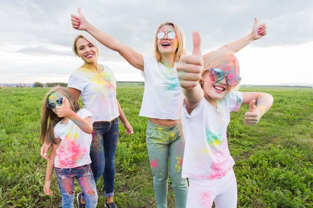 Holi festival, holidays and happiness concept - young teens and women in colors have fun outdoor