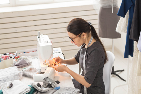 Dressmaker, tailor and seamstress concept - young fashion designer working in her showroom