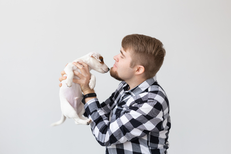 people, pets and animals concept - young man kissing jack russell terrier puppy on white backgroundの写真素材