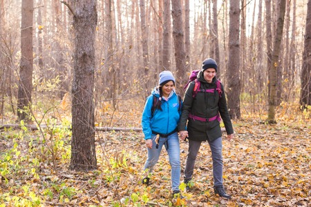 adventure, travel, tourism, hike and people concept - smiling couple walking with backpacks over...