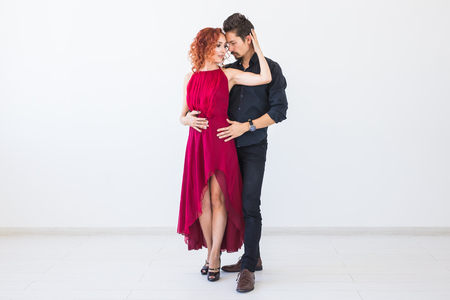 Social dance, bachata, kizomba, salsa, tango concept - Woman dressed in red dress and man in a black costume over white background with copy spaceの写真素材