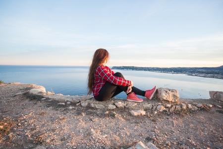 Travel, adventures and nature concept - Female tourists sitting alone on the mountainの写真素材