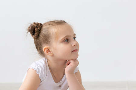 Children and kids concept - Portrait of beautiful little child girl holding her chin on hand and looking upの写真素材