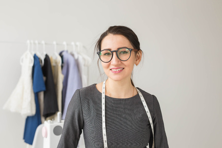 Dressmaker, fashion designer and tailor concept - Young dressmaker woman over clothes rack with dresses backgroundの写真素材