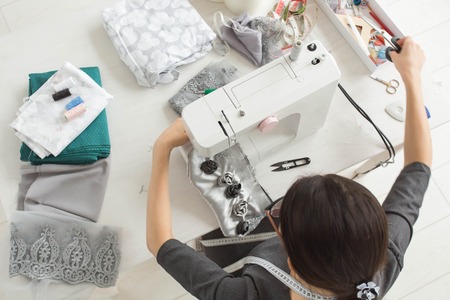 Tailor, fashion and seamstress concept - young female fashion designer in her showroom, top viewの写真素材