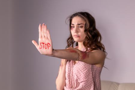 Domestic violence, protesting and people concept - brunette woman expressing denial with STOP on her hand on grey roomの写真素材