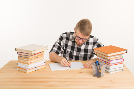 People, knowledge and education concept - Happy student sits at the table and makes notes in a...