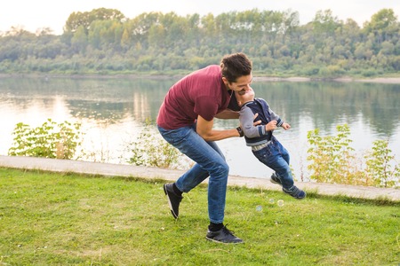 Childhood, family concept - father playing with son near the lake