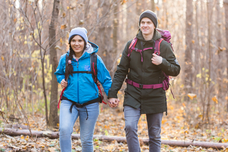adventure, travel, tourism, hike and people concept - smiling couple walking with backpacks over autumn natural backgroundの写真素材