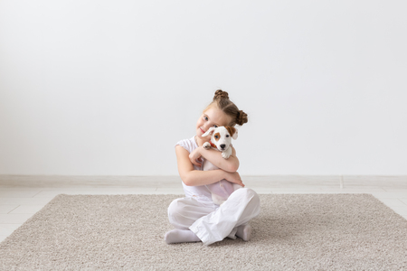 people, children and pets concept - little child girl sitting on the floor with cute puppy Jack Russell Terrierの写真素材