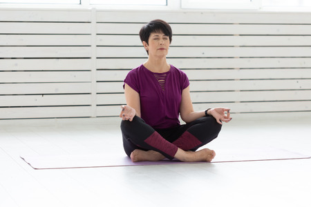 Yoga, harmony, people concept - Middle aged woman sitting in lotus positionの写真素材