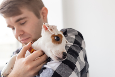 people, pets and animals concept - close up of young man holding puppyの写真素材