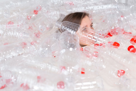Plastic pollution problem and environment protection. Weak tired woman in a pile of plastic bottles. Save Earth concept. Clean our nature.の写真素材