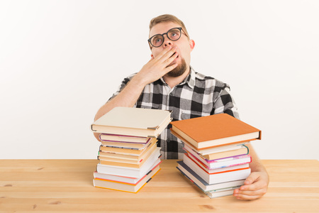 People, exam and education concept - Exhausted and tired student dressed in plaid shirt sitting at...