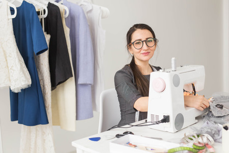 People, tailor and fashion concept - High angle view portrait of smiling fashion designer in glasses sitting at a tableの写真素材