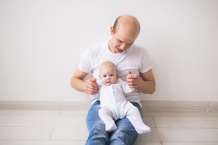 Infant, family and children concept - Close up portrait of a baby daughter in the fathers armsの写真素材