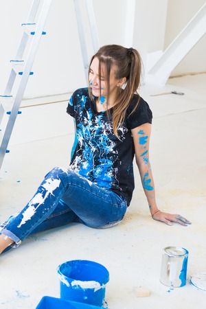 People, renovation and interiors concept - Young woman sitting on the white floor and have fun at the breakの写真素材