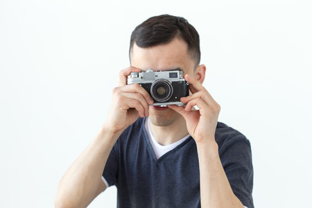Vintage, photographer and people concept - handsome asian man with retro camera over white...