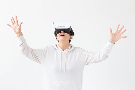 Positive pretty middle-aged woman in a white sweater watching a movie with glasses of virtual reality. The concept of futurism and new technologies.の写真素材