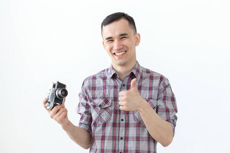 Technologies, photographing and people concept - handsome asian young man with retro camera over white backgroundの写真素材
