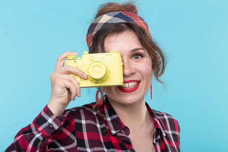 Closeup portrait of a positive beautiful young woman wearing a plaid shirt taking pictures with a...