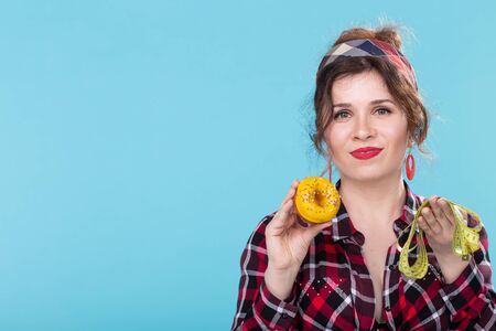 Pin-up woman with measuring tape and doughnut, copy space over the blue backgroundの写真素材