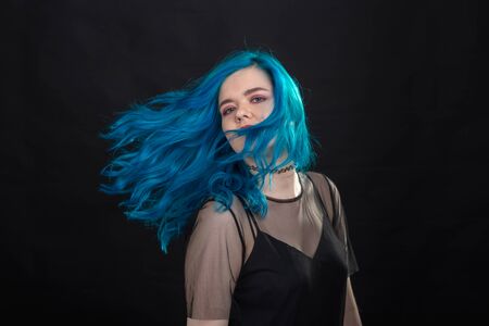 Style, fashion and hair concept - close-up portrait of young woman in black dress with blue hair on...