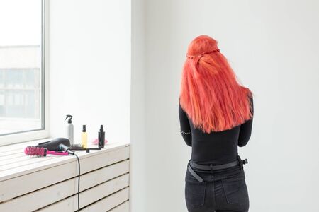 Beautiful stylish girl with shiny red straight long hair. Care and hair products.