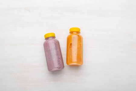 Two bottles with orange and blueberry juice lie on a white table. The concept of proper nutrition...
