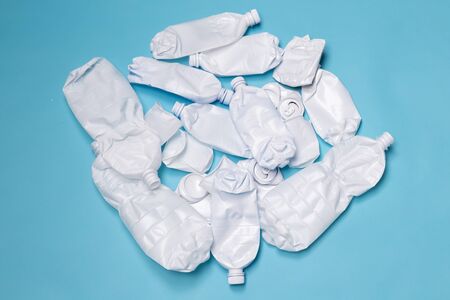 Crumpled plastic bottles lies on a blue background. Concept of pollution of the environment with...