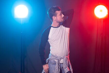 Dance, hip-hop and reggaeton concept - young man dancing over the lights.